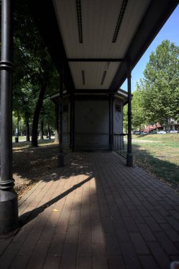 Closed kiosk in the shade under a few trees in a park on a sunny day