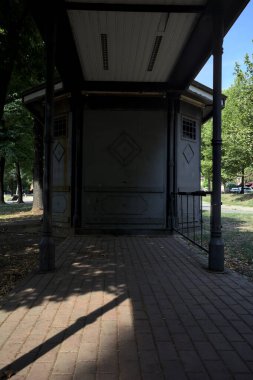 Closed kiosk in the shade under a few trees in a park on a sunny day