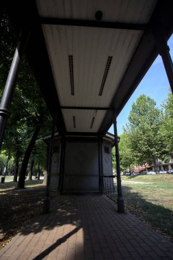 Closed kiosk in the shade under a few trees in a park on a sunny day