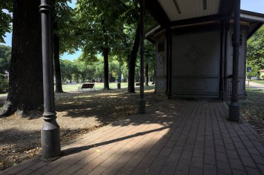 Closed kiosk in the shade under a few trees in a park on a sunny day