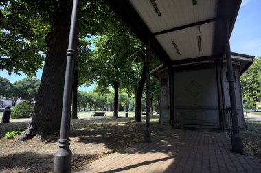 Closed kiosk in the shade under a few trees in a park on a sunny day