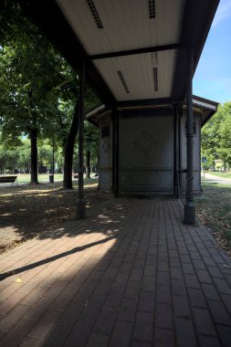Closed kiosk in the shade under a few trees in a park on a sunny day