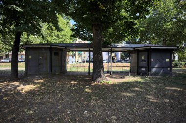 Closed kiosk in the shade under a few trees in a park on a sunny day
