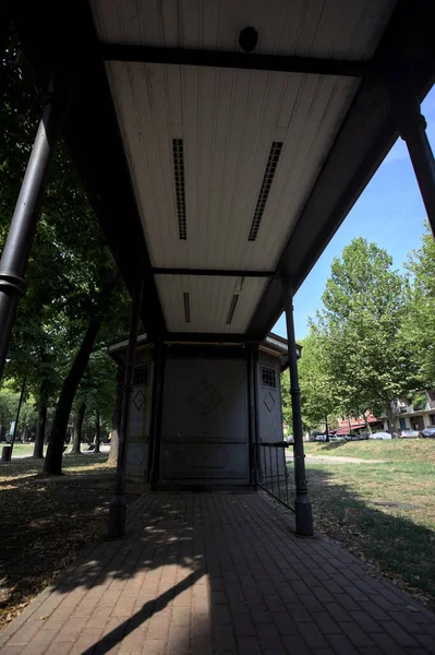 Closed kiosk in the shade under a few trees in a park on a sunny day