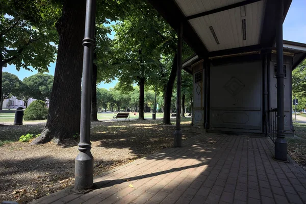 Closed kiosk in the shade under a few trees in a park on a sunny day