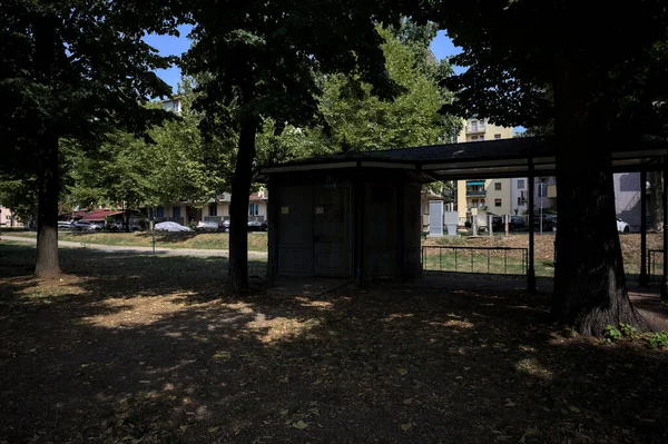 Closed kiosk in the shade under a few trees in a park on a sunny day