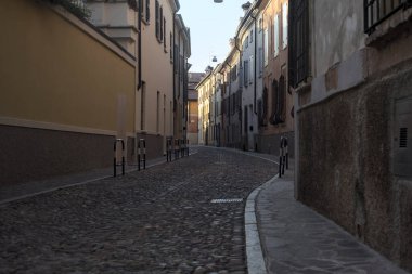 Yolun bir tarafındaki bir binanın balkonunda, gölgede kısmen boş bir cadde var.