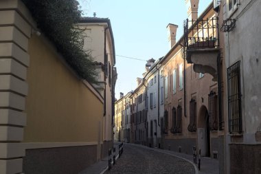 Yolun bir tarafındaki bir binanın balkonunda, gölgede kısmen boş bir cadde var.