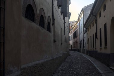 Gün batımında bir İtalyan kasabasının gölgesinde, kaldırımlı ve dar bir sokakta eğil.