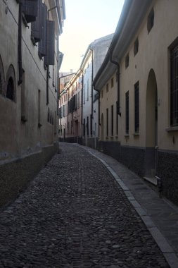 Gün batımında bir İtalyan kasabasının gölgesinde, kaldırımlı ve dar bir sokakta eğil.
