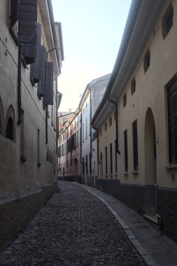 Gün batımında bir İtalyan kasabasının gölgesinde, kaldırımlı ve dar bir sokakta eğil.