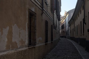 Gün batımında bir İtalyan kasabasının gölgesinde, kaldırımlı ve dar bir sokakta eğil.