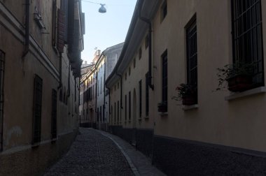 Gün batımında bir İtalyan kasabasının gölgesinde, kaldırımlı ve dar bir sokakta eğil.