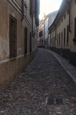 Gün batımında bir İtalyan kasabasının gölgesinde, kaldırımlı ve dar bir sokakta eğil.