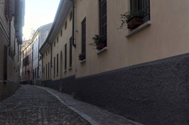 Gün batımında bir İtalyan kasabasının gölgesinde, kaldırımlı ve dar bir sokakta eğil.