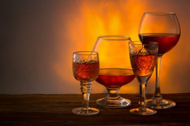 Büyük bardaklarda güçlü alkollü içecekler ve arka planda, ahşap bir masada küçük kadehler. Tentür, konyak, viski, brendi, rom, içki stokta..