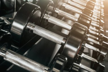 Dambıllar spor salonundaki raflara dizilmişti. Dambıl sırası. Spor malzemeleri dambılları.