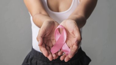 Göğüs kanseri farkındalığı için pembe kurdele tutan kadın elleri, göğüs kanseri. Sağlık ve Tıp Konsepti.