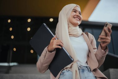 Akıllı telefon kullanan Müslüman bir kadın. Müslüman iş kadını gülümsüyor ve akıllı telefon arıyor..