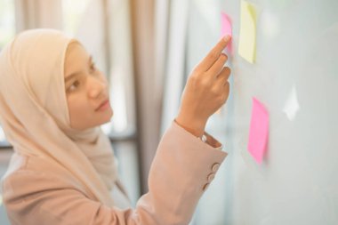 Elde çalışan Müslüman iş kadınının üzerine yapıştırma yapıştırması yapıştırın. Beyin fırtınası ve yaratıcılık kavramı.