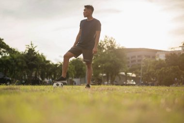 Yeşil sahada futbol oynayan adam. Asyalı futbolcu futbol oynuyor.