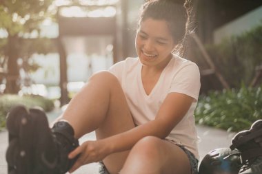 Mutlu kadın yaz günü paten kayıyor. Asyalı kadın kendinden emin, güzel..