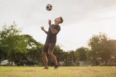 Yeşil sahada futbol oynayan adam. Asyalı futbolcu futbol oynuyor.