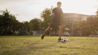 Yeşil sahada futbol oynayan adam. Asyalı futbolcu futbol oynuyor.