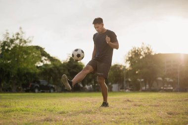 Yeşil sahada futbol oynayan adam. Asyalı futbolcu futbol oynuyor.