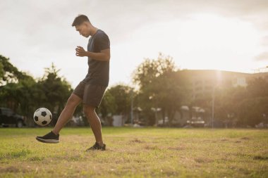 Yeşil sahada futbol oynayan adam. Asyalı futbolcu futbol oynuyor.