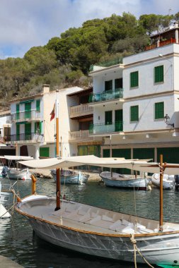 Balıkçı köyü Cala Figuera 'da yeşil kepenkleri ve kapıları olan beyaz evler ve evlerin yanında duran tekneler. Cala Figuera. 
