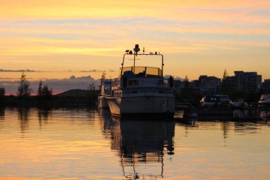 Günbatımında Vesijarvi gölünün suyuna beyaz bir yat yansıdı. Lahti. Finlandiya.