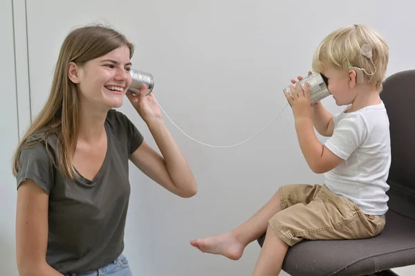 Pojke Med Cochlear Implantat Spelar Plåtburk Telefon Stockbild