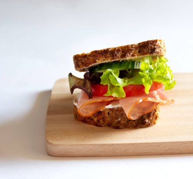 Sebzeli ve jambonlu sandviç. Tahta tahta, beyaz arkaplan.