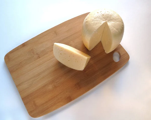 Queijo. Cabeça de queijo redonda em uma tábua de madeira. Pedaço de queijo. — Fotografia de Stock