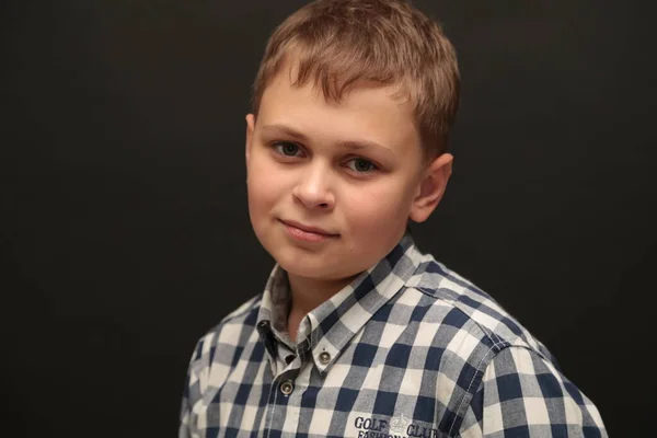 Portret van een jongen in een shirt op een zwarte achtergrond. — Stockfoto