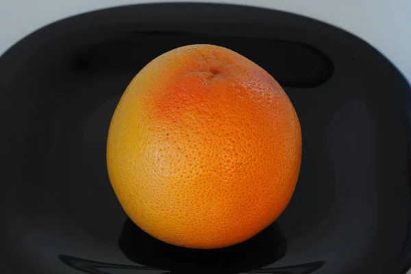 과일은 감 귤류의 과 일이다. 검은 접시 위에 있는 오렌지 회색 과일. — 스톡 사진