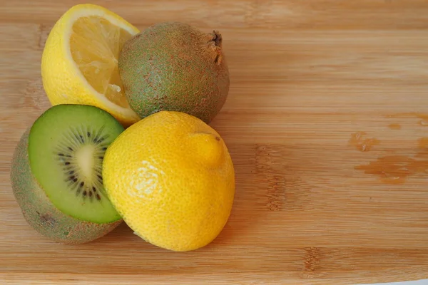 Citrus. Kiwi and lemon cut in half. A wooden background. Close-up. — Stock Photo, Image