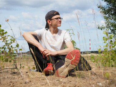 Genç bir adam kumsalda bir parkta oturuyor..