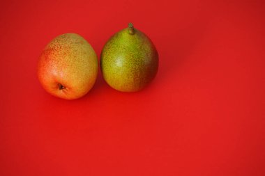 Olgun meyve. Kırmızı zemin üzerinde iki güzel armut. 