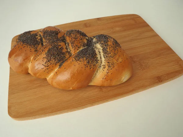Tahta tepside taze ekmek. Sıcak bir çörek ve haşhaş..