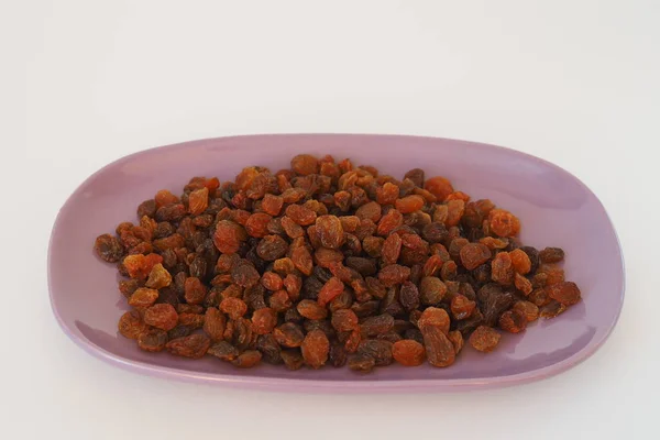 Raisins dark sprinkled in a plate, close-up. — Stock Photo, Image