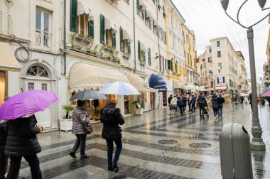 San Remo, Italya-24 Şubat, 2018. Şemsiyeler altında yürüyen insanlar. Avrupa 'nın güneyindeki şehirler mimarisi ve türleri.