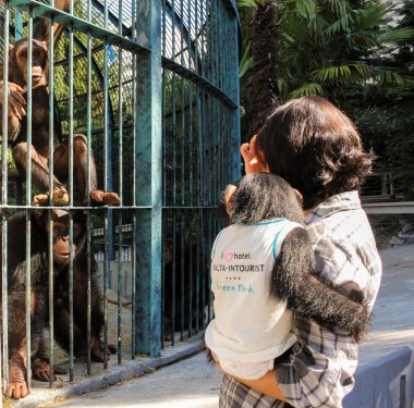 Bir kızla bir kafes içinde bir bebek maymun.