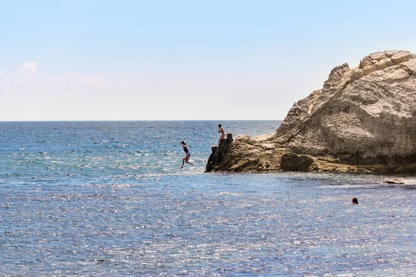 Chica saltando desde un acantilado en el mar . — Foto de Stock