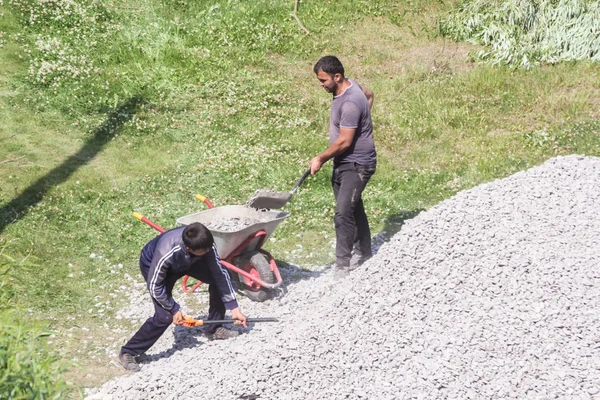 Trabajadores cargan piedra triturada en una carretilla . — Foto de Stock