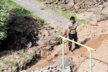 İşçi kürek bir siper de kum atar.