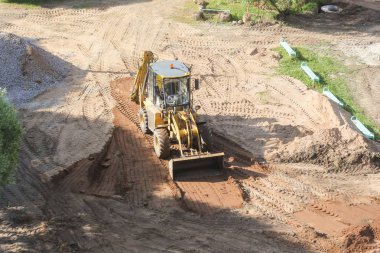 Bir ekskavatör kova kum site planlıyor.