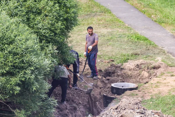 Työntekijät hautaavat kaivon lähelle ojan. . — kuvapankkivalokuva