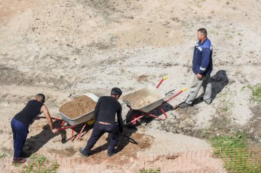 İşçi arabaları kum yükler.